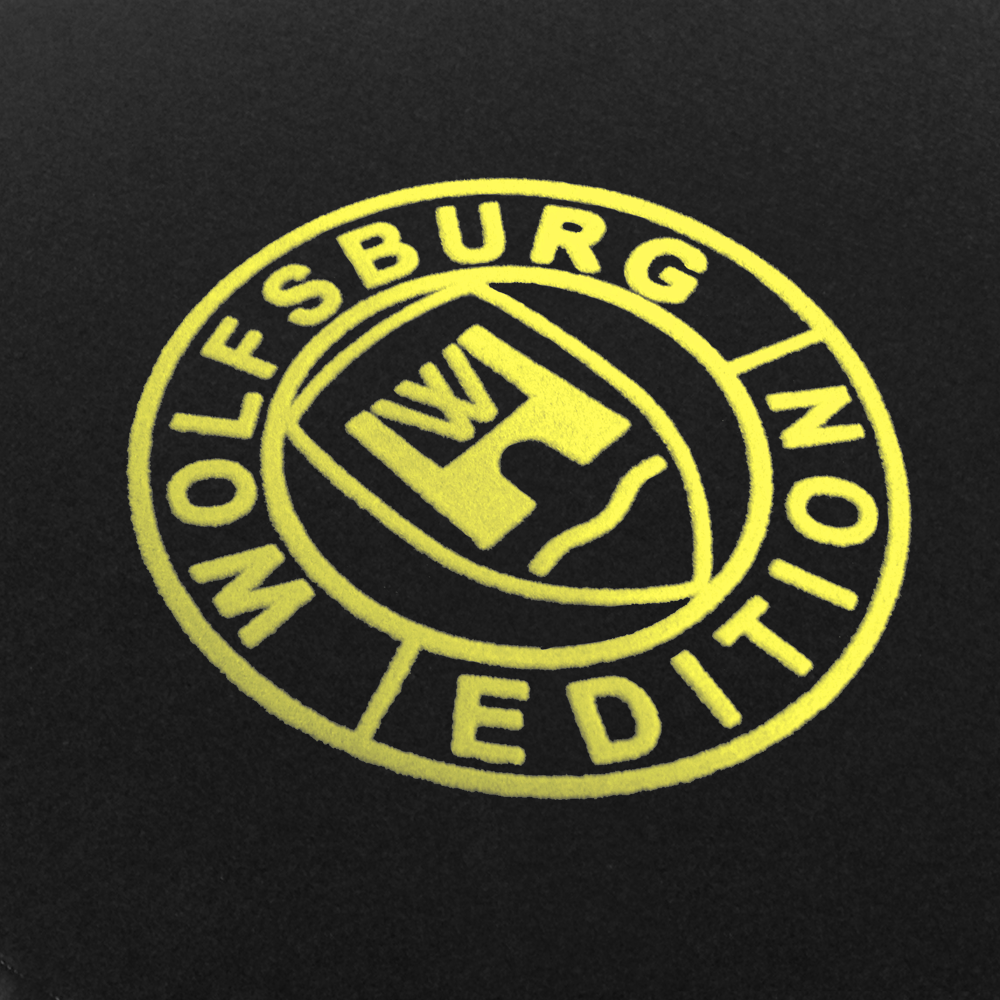 Das Wolfsburg Editions Logo auf einem schwarzen Teppich und das Logo ist in safran.