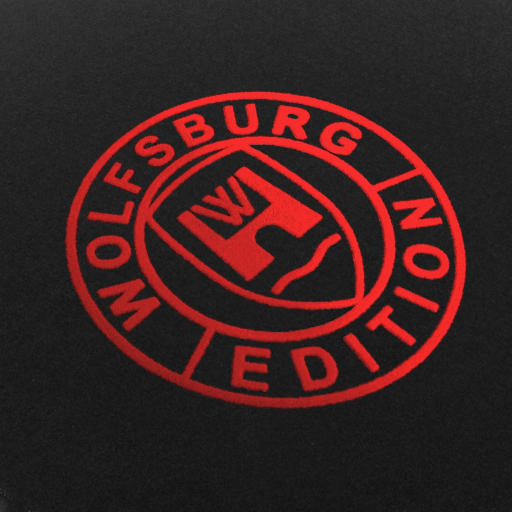 Fussmatte_WOB-Wolfsburg-Edition_Detail-rot Das Wolfsburg Editions Logo auf einem schwarzen Teppich und das Logo ist in rot.
